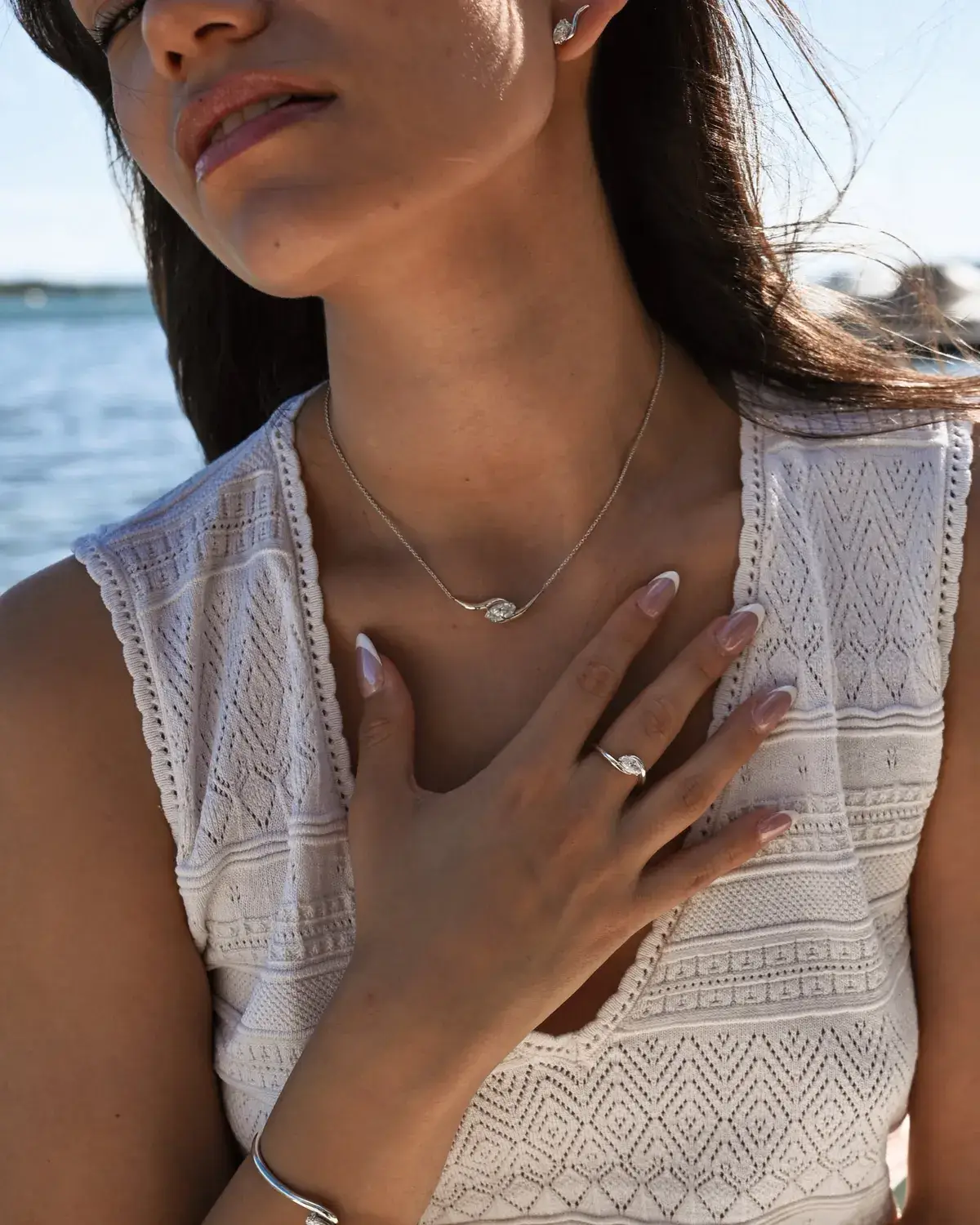 Modèle portant le collier et la bague HALO en argent 925, main sur la poitrine